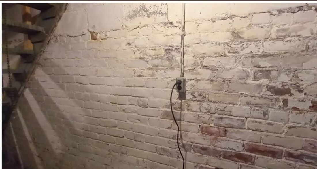 Before: damaged basement brick wall with failing mortar and moisture staining